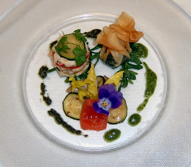Gourmet-Tellergericht mit Meeresfrüchten, Gemüse, essbaren Blüten und grüner Sauce auf einem weißen Teller – eine elegante Kreation, inspiriert vom Goldenen Karpfen in Fulda.