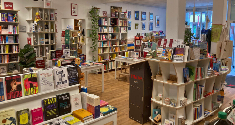 Verkaufsraum der Buchhandlung Ulenspiegel in Fulda mit Bücherregalen, Büchertischen und Holzboden