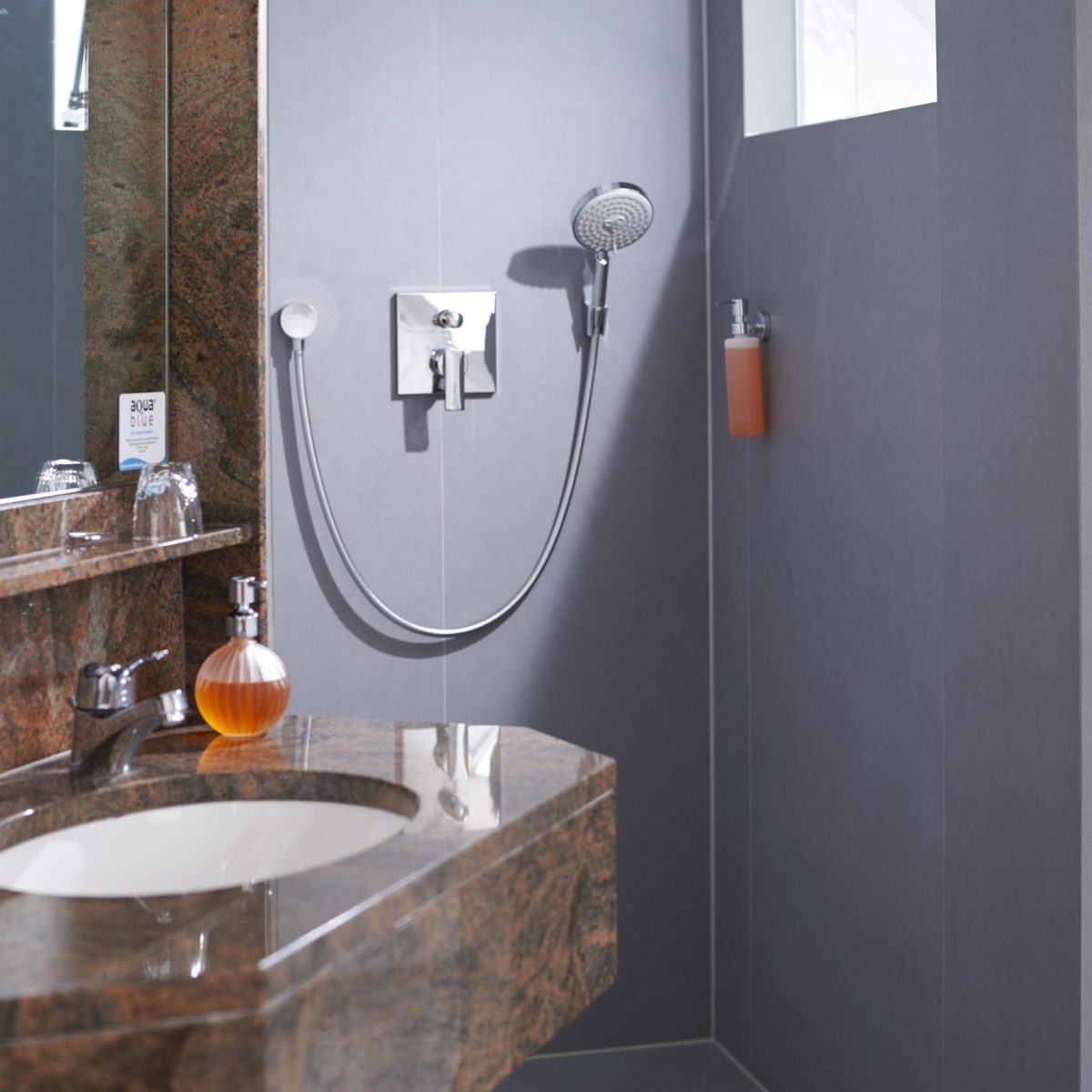 Modernes Badezimmer mit Marmorwaschbecken, wandmontierter Dusche und einem Fischmotiv auf dem Duschboden.